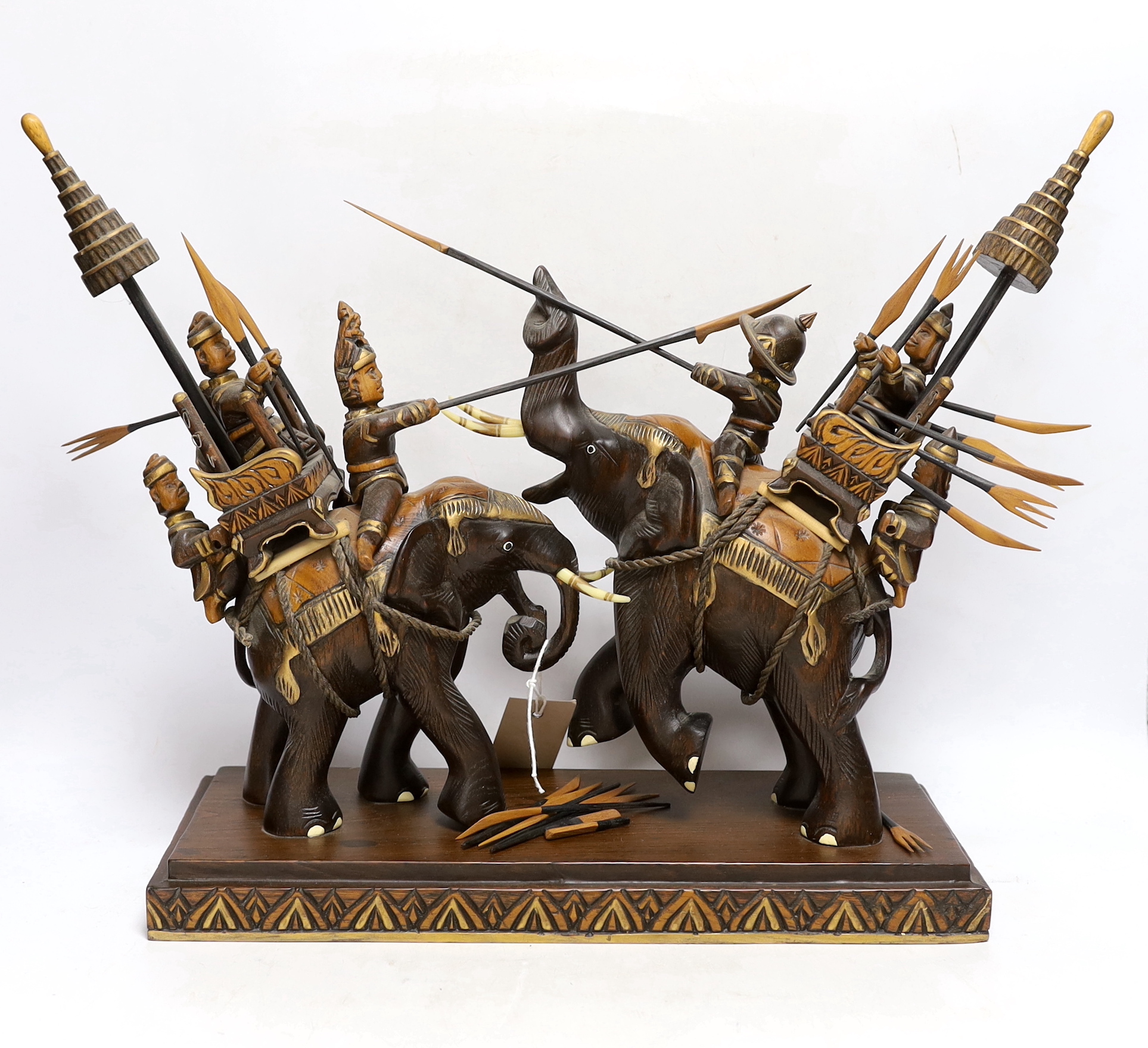A pair of South Asian carved wood fighting elephants with mahouts, 37cm high x 50cm wide